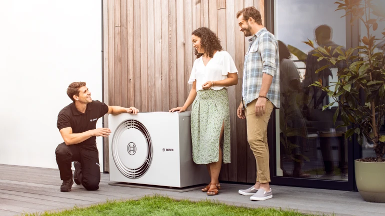 couple and installer standing by heat pump