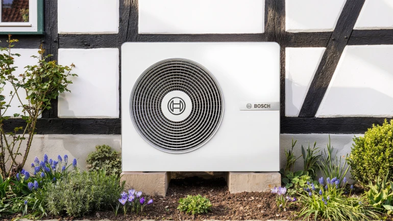 weißes Haus mit Wärmepumpe davor stehend