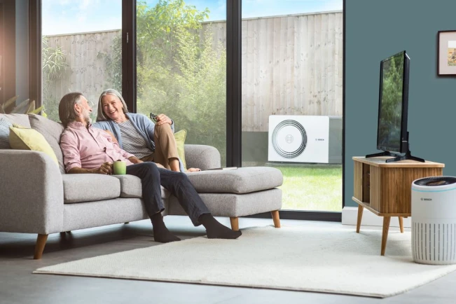 Paar mit Wärmepumpe im Hintergrund