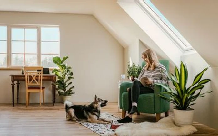 Frau mit Hund befindet sich im Wohnzimmer und genießt Wärme der Fußbodenheizung