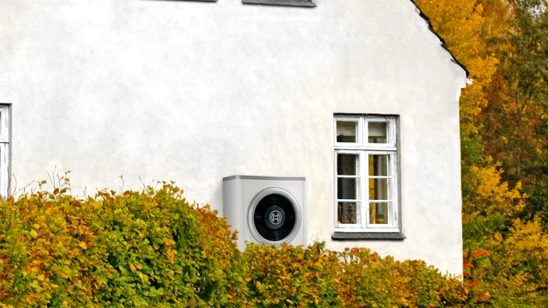 weißes Haus mit Wärmepumpe davor stehend