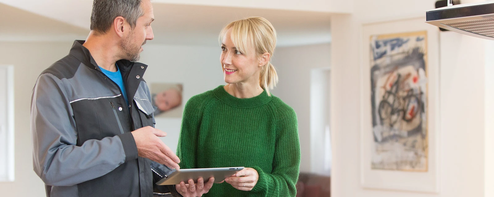 An installer explains the function of a heat pump to a woman