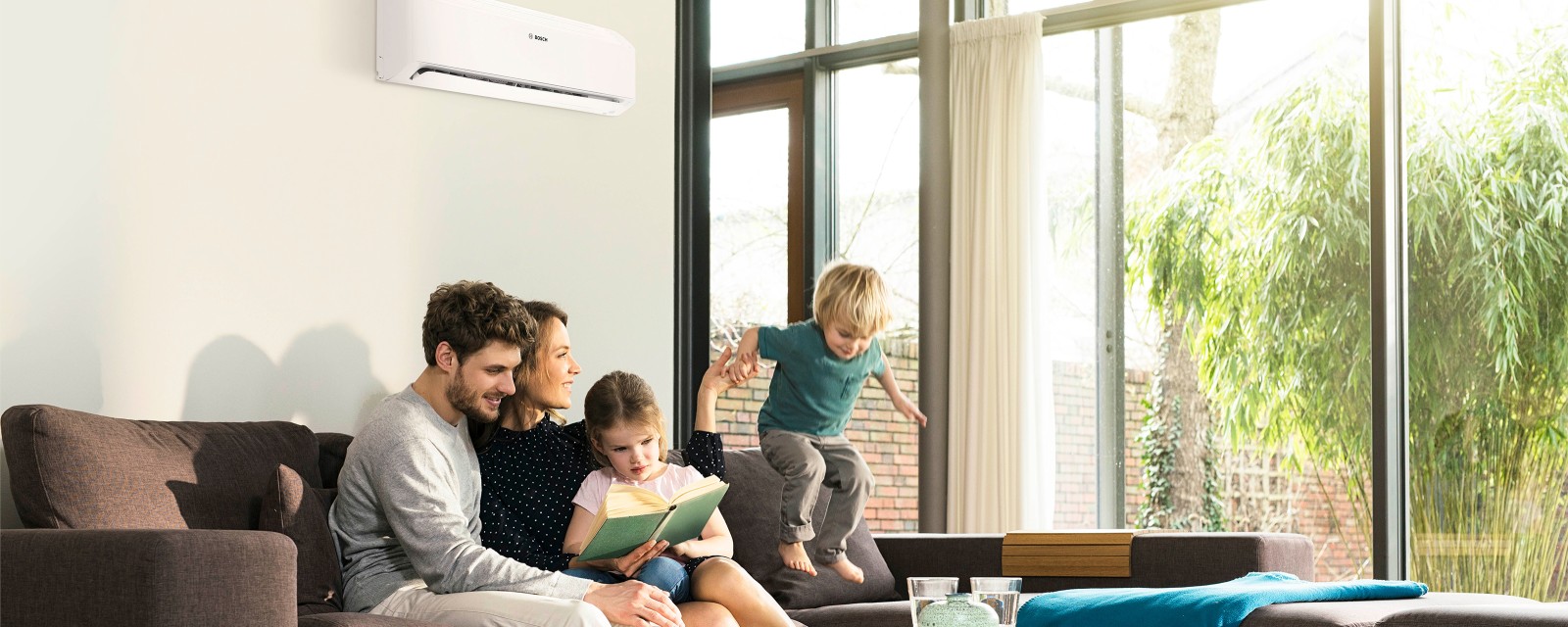 Family sitting on the sofa in front of an air conditioning system Family sitting on the sofa in front of an air conditioning system