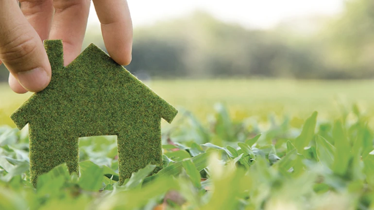 Een klein, groen vilten huisje staat op een groen veld.
