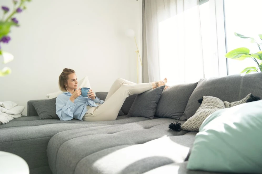 Woman relaxes on couch and enjoys the cool apartment