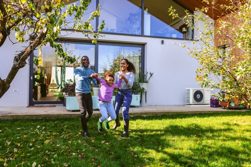 Familie die aan het spelen is met op de achtergrond een buitenunit van de hybride warmtepomp 3400