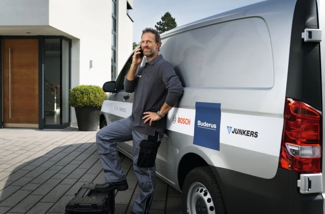 Un installateur téléphone à coté de sa camionette