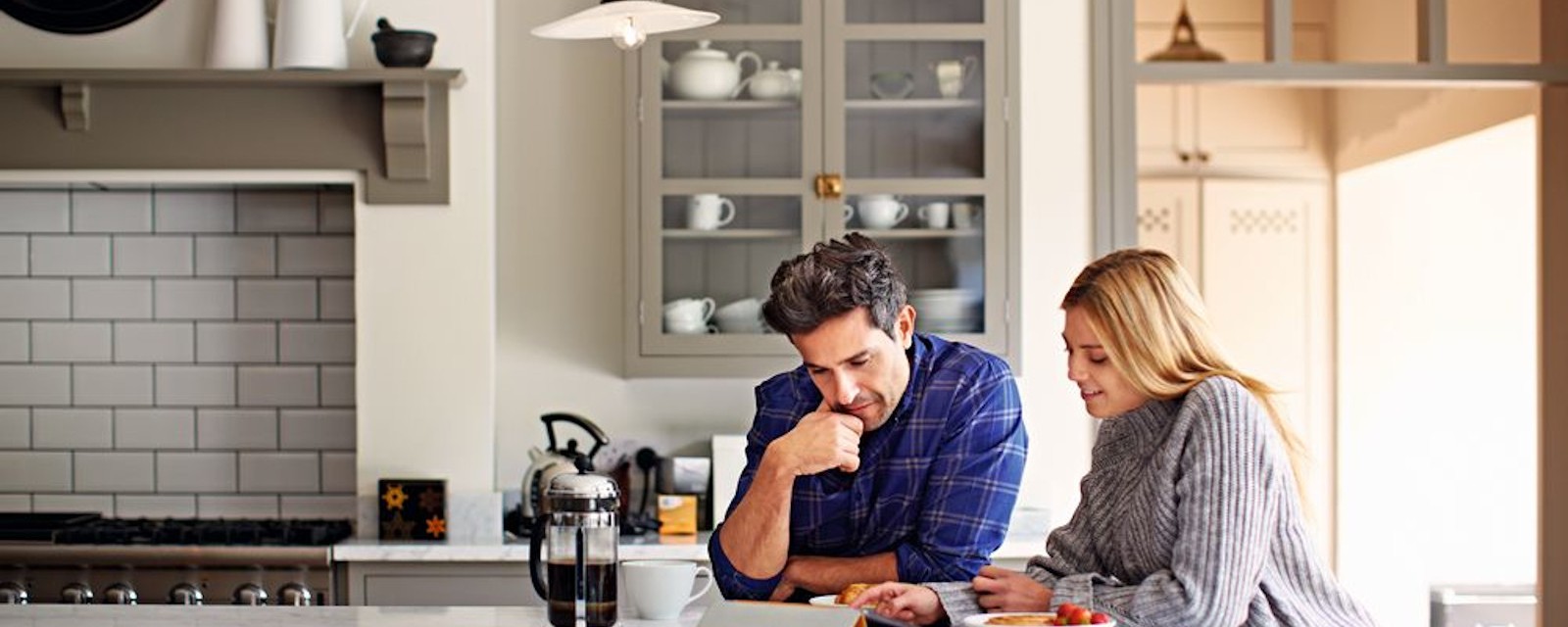 A young couple at the kitchen table talks about the pros and cons of heat pump or gas heating. A young couple at the kitchen table talks about the pros and cons of heat pump or gas heating.
