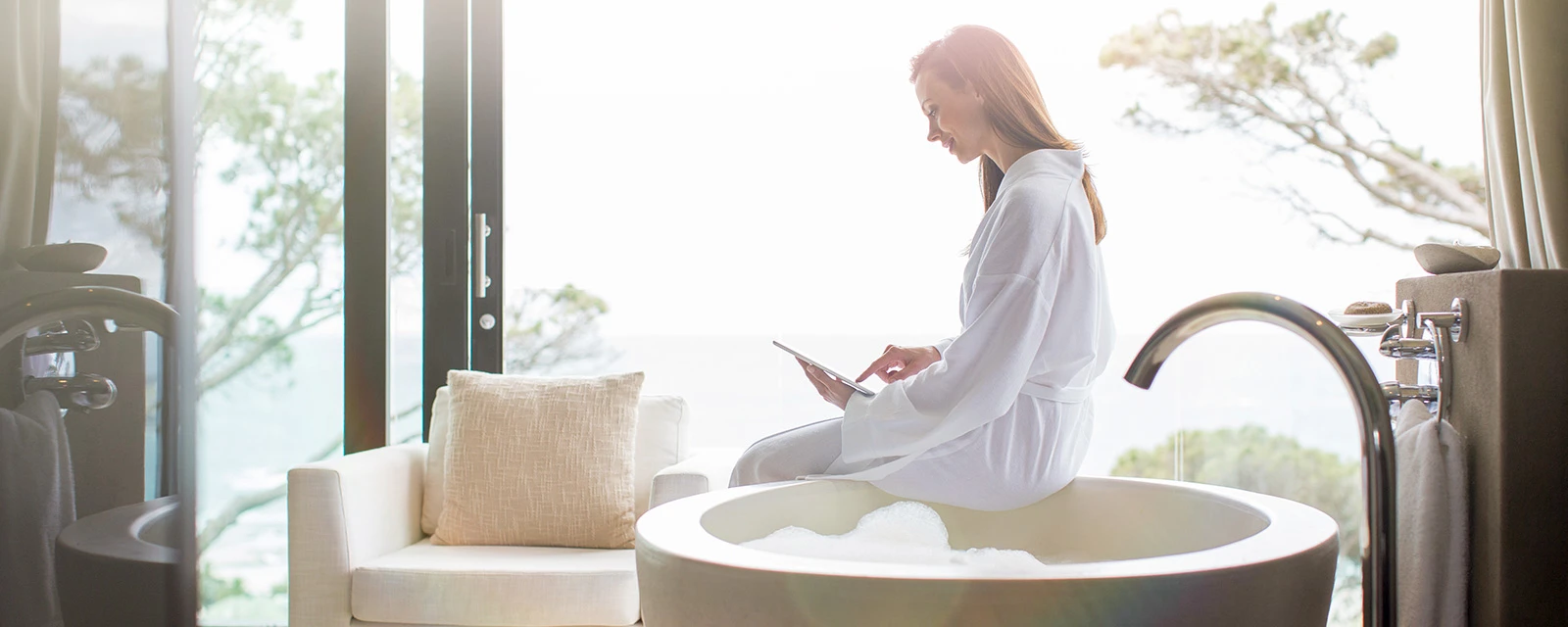 Eine Frau mit Tablet sitzt auf einer Badewanne