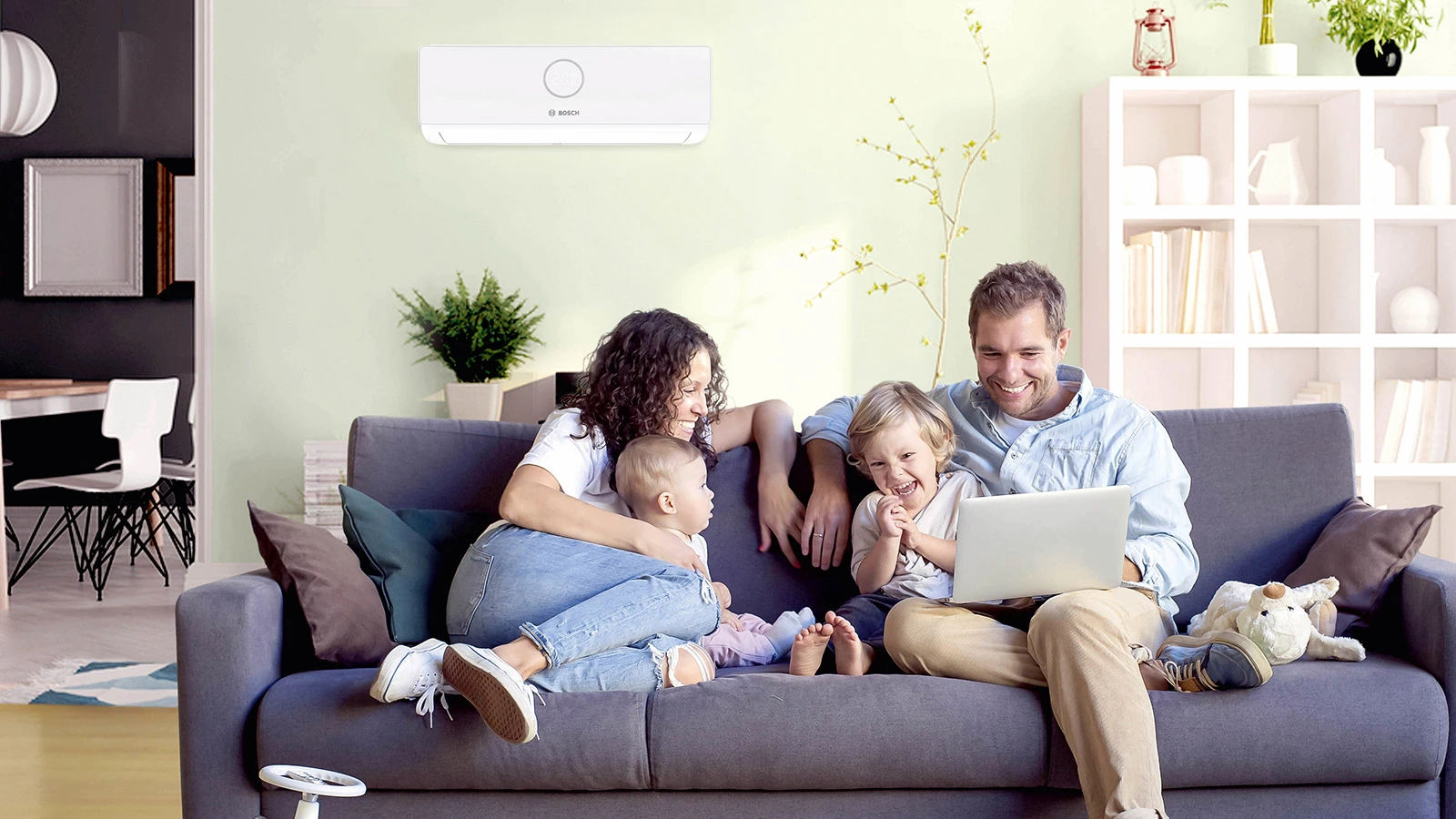 Eine Familie sitzt zusammen auf einem Sofa; im Hintergrund sieht man eine Klimaanlage von Bosch an der Wand.