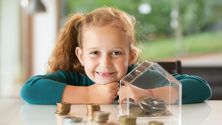 Ein Mädchen sitzt vor einem Sparhaus.
