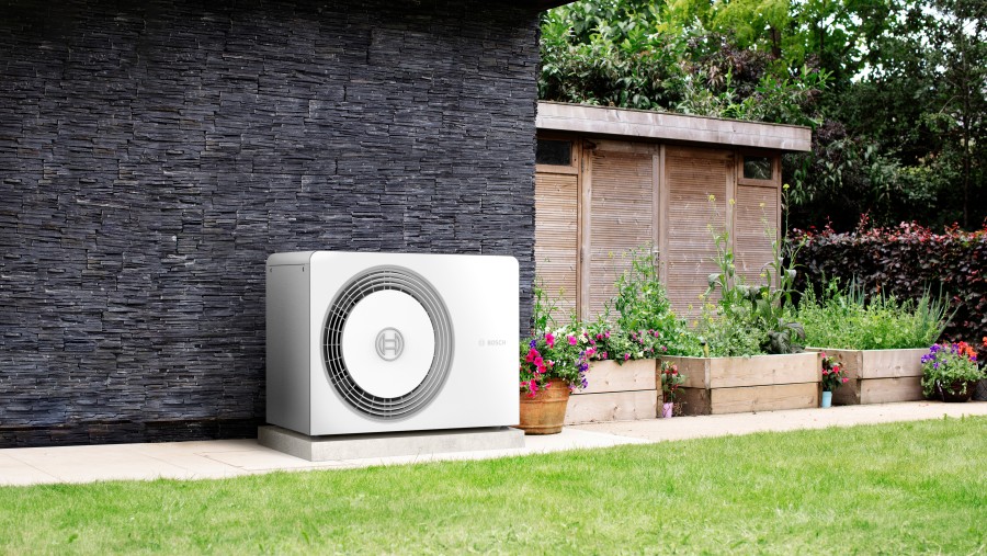 Bosch Wärmepumpe Compress 5800i AW im Gartenbereich neben Topfpflanzen stehend. Bosch Wärmepumpe Compress 5800i AW im Gartenbereich neben Topfpflanzen stehend.
