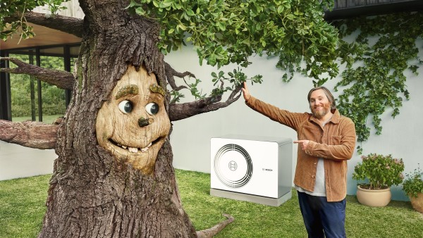 Ein Baum mit einem lächelnden Gesicht gibt einem Mann ein High-Five - während im Hintergrund eine Wärmepumpe zu erkennen ist.