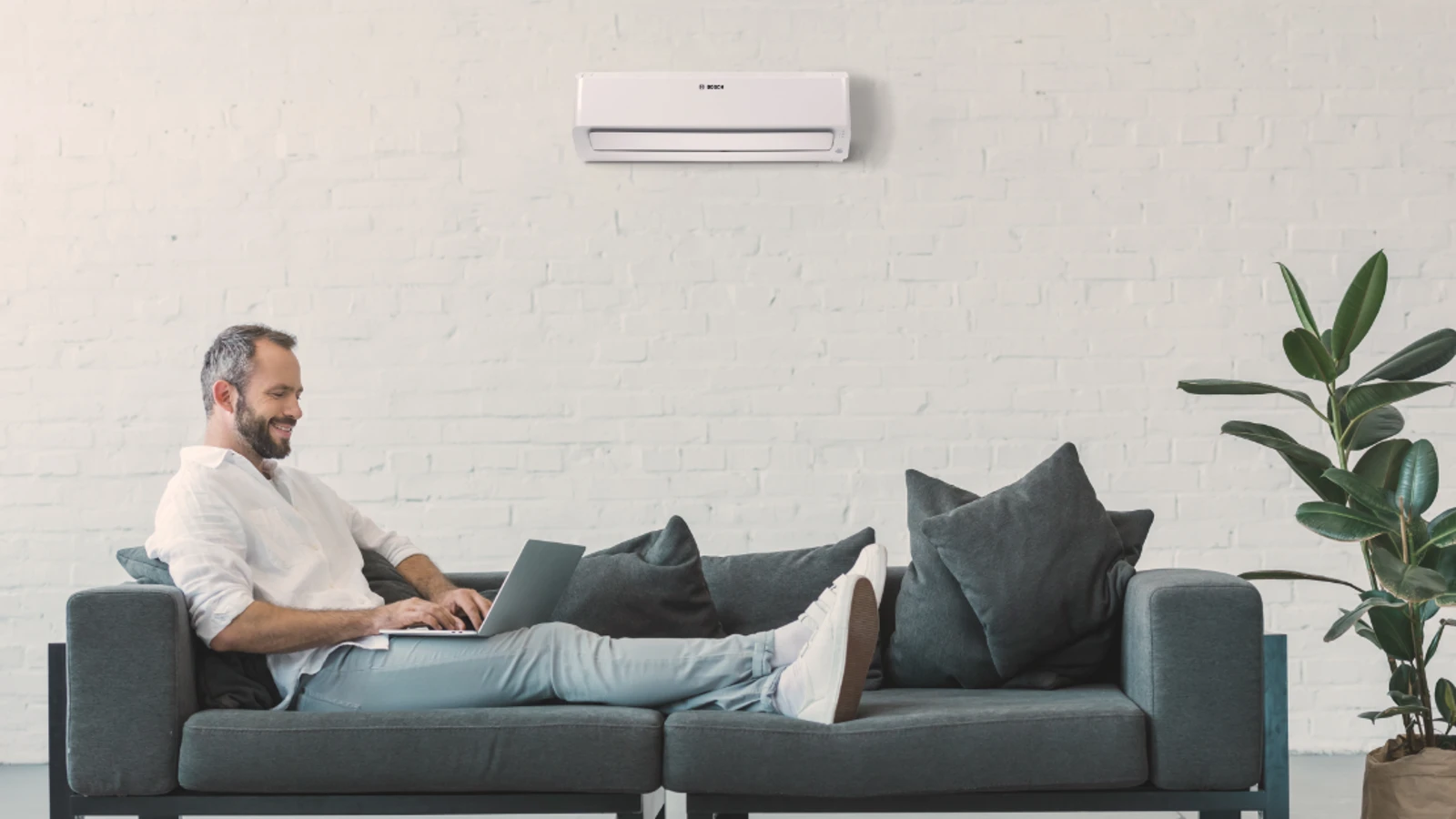 Eine Klimaanlage hängt an der Decke, davor sitzt ein Mann, der liest. Im Hintergrund ist eine Treppe, die in eine obere Etage führt.