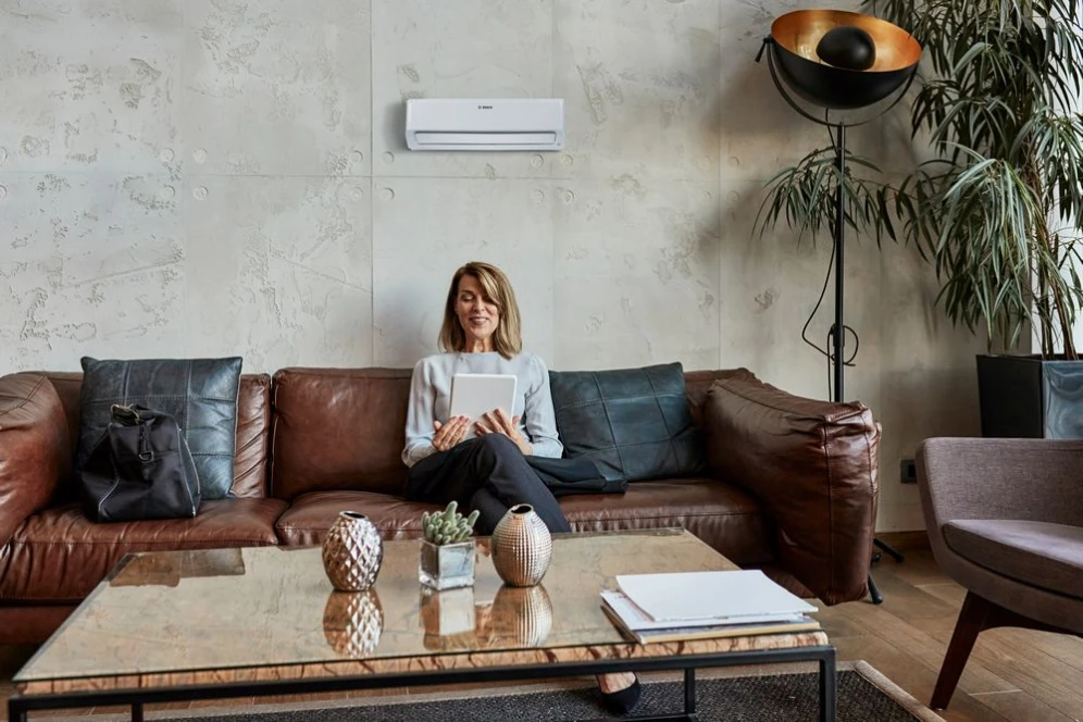 Frau sitzt auf der Couch und benutzt ungestört vom leisen Klimagerät ein Tablet