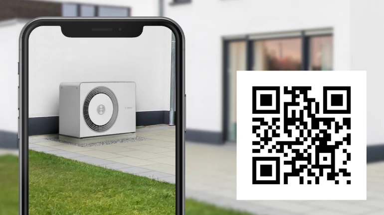 Auf einem Smartphone ist die Kamera geöffnet und es wird eine Wärmepumpe von Bosch virtuell vor einem Haus platziert, der dazugehörige QR-Code befindet sich unten rechts im Bild.