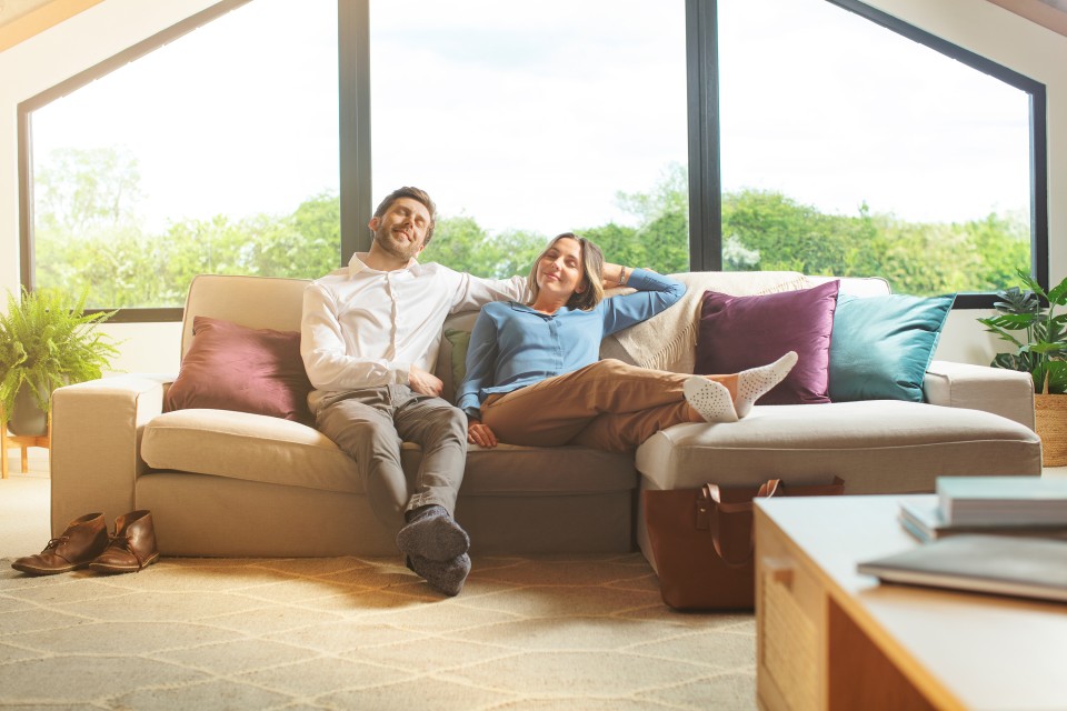 Ein Paar sitzt im Wohnzimmer auf dem Sofa und sieht sehr entspannt aus. Ein Paar sitzt im Wohnzimmer auf dem Sofa und sieht sehr entspannt aus.