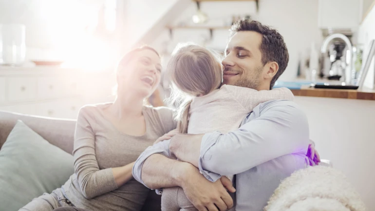 Eine Familie sitzt auf einem Sofa und lacht miteinander.