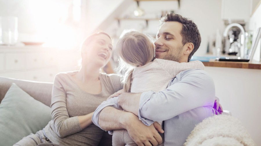 Eine Familie sitzt auf einem Sofa und lacht miteinander. Eine Familie sitzt auf einem Sofa und lacht miteinander.