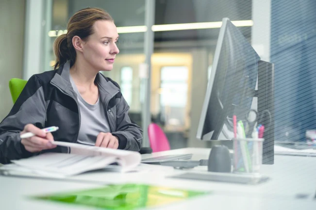 Installateurin sitzt an einem Tisch und schaut auf einen Computer.