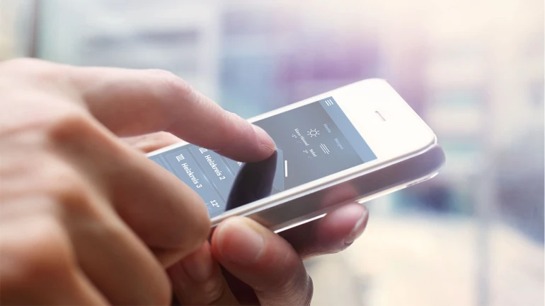 Eine Person hält ein Smartphone in der Hand auf dem eine Heizung geregelt werden kann.