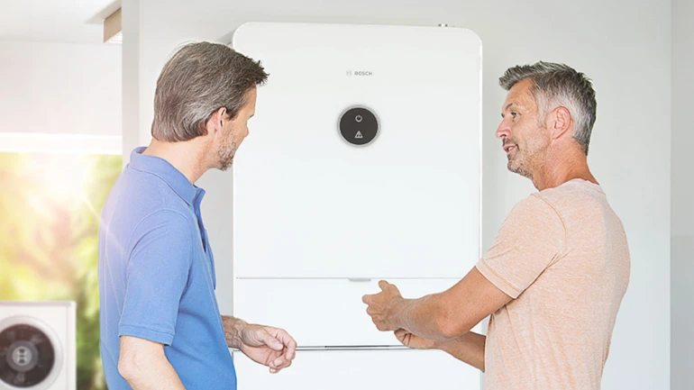 Zwei Männer sprechen über eine Bosch Wärmepumpe und ihre Funktionen.