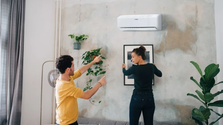 Klimagerät Climate Class 6000i an der Wand montiert, ein Paar hängt ein Bild darunter auf.
