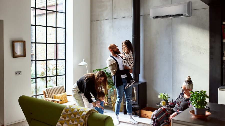 Familie befindet sich in einem modernen Wohnraum, an der Wand hängt die Bosch Single-Split Klimaanlage Climate Class 8000i Familie befindet sich in einem modernen Wohnraum, an der Wand hängt die Bosch Single-Split Klimaanlage Climate Class 8000i
