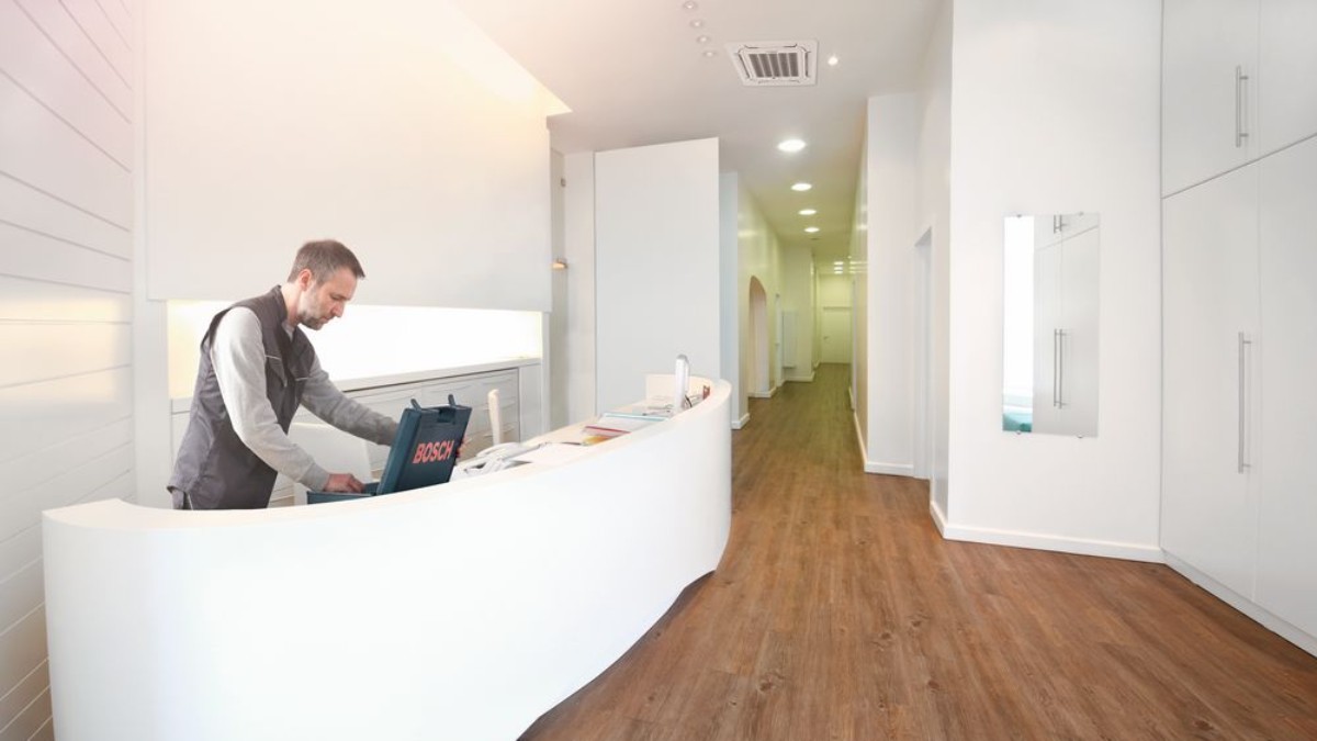 Installateur steht hinter dem Tresen einer Praxis mit geöffnetem Werkzeugkoffer. Installateur steht hinter dem Tresen einer Praxis mit geöffnetem Werkzeugkoffer.
