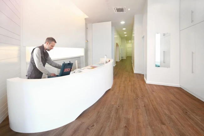 Ein Bosch Installateur steht hinter einem Tresen, an der Decke ist eine Klimaanlagen Deckenkassette installiert.