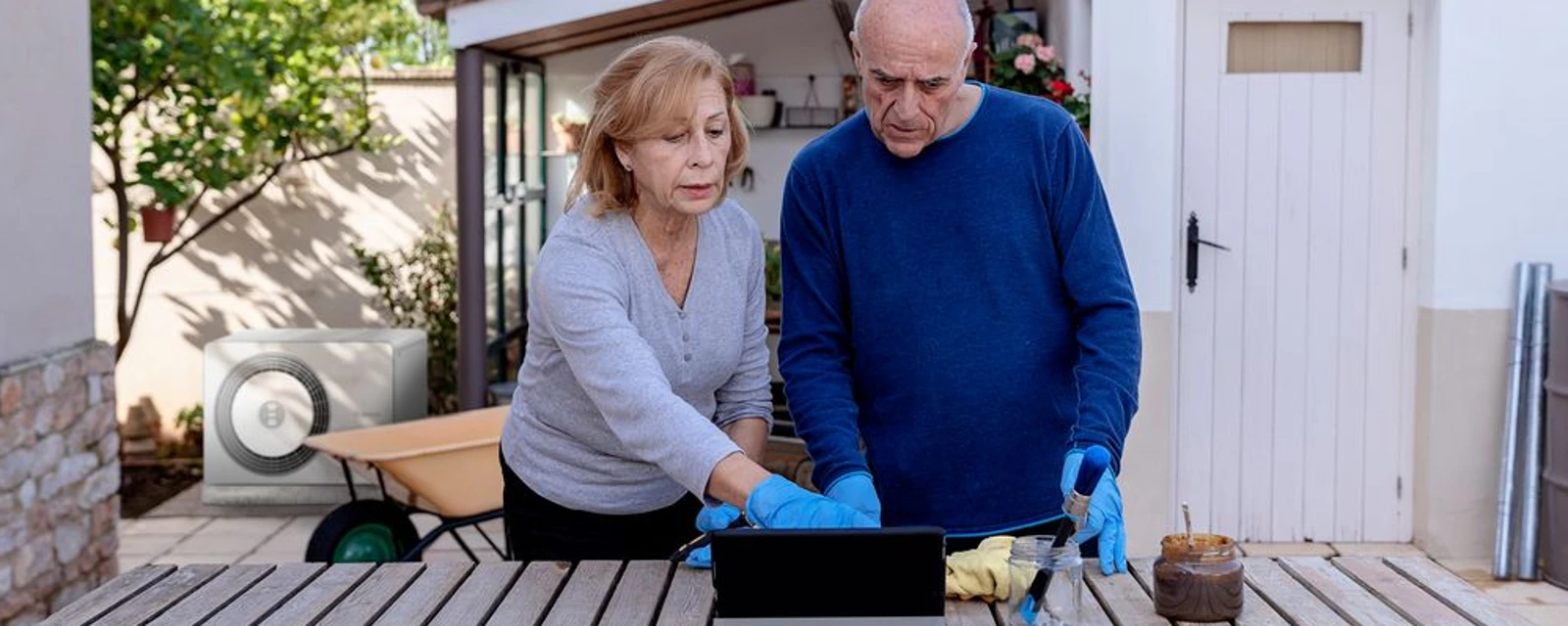 Hintergrund: Bosch Wärmepumpe Compress 5800, Vordergrund:Mann und Frau stehen auf Terasse und schauen auf ein Tablet