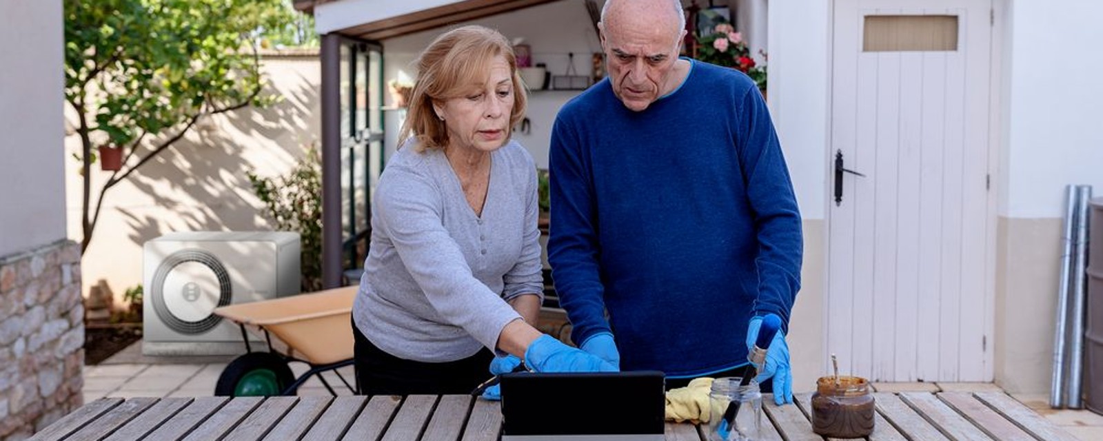 Hintergrund: Bosch Wärmepumpe Compress 5800, Vordergrund:Mann und Frau stehen auf Terasse und schauen auf ein Tablet Hintergrund: Bosch Wärmepumpe Compress 5800, Vordergrund:Mann und Frau stehen auf Terasse und schauen auf ein Tablet
