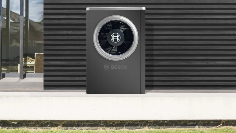 Farbige Wärmepumpe steht vor dem Haus