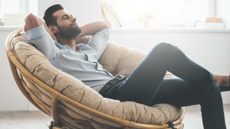 Mann sitzt zurückgelehnt auf einem Stuhl