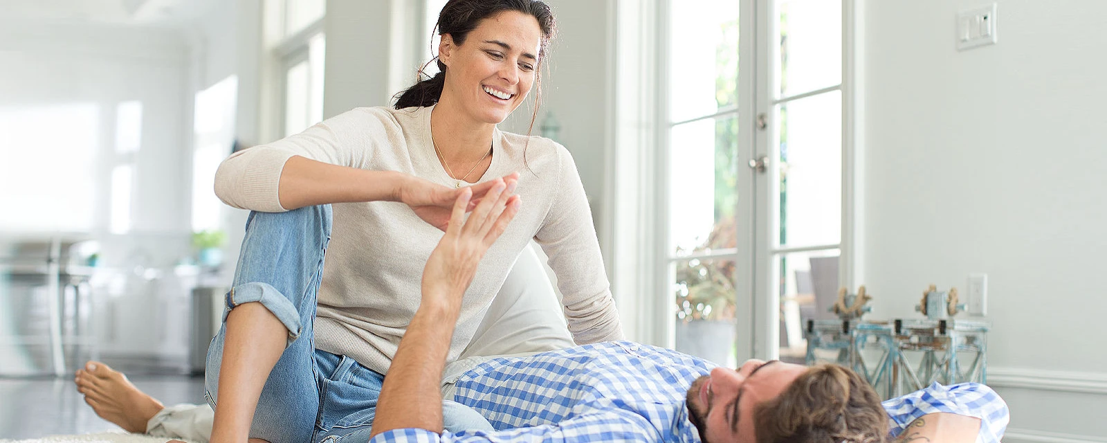 Frau und Mann sitzen auf dem Fußboden und genießen die Wärme der Fußbodenheizung.