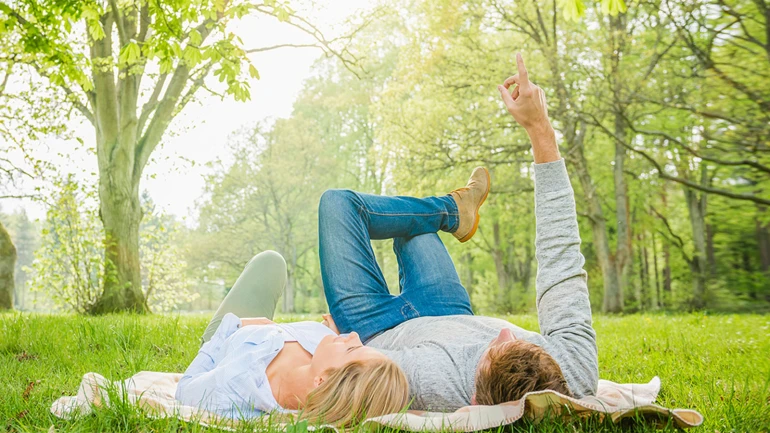 Ein Paar liegt auf einer grünen Wiese mit Bäumen