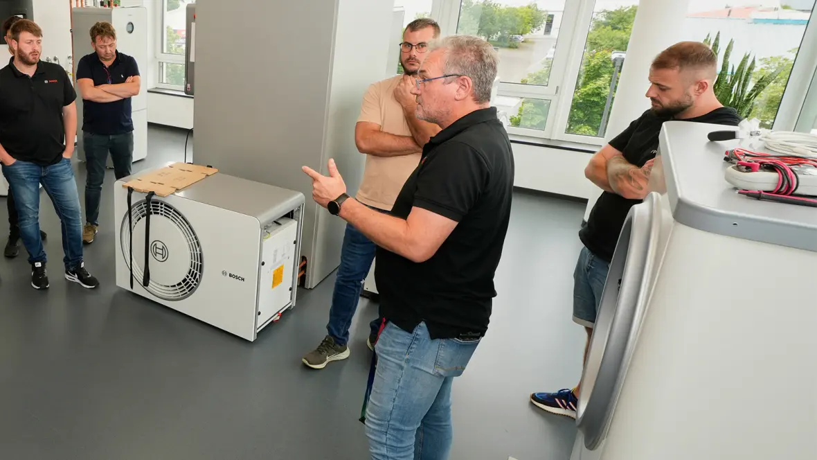 Mehrere Männer stehen um eine Wärmepumpe herum und unterhalten sich.