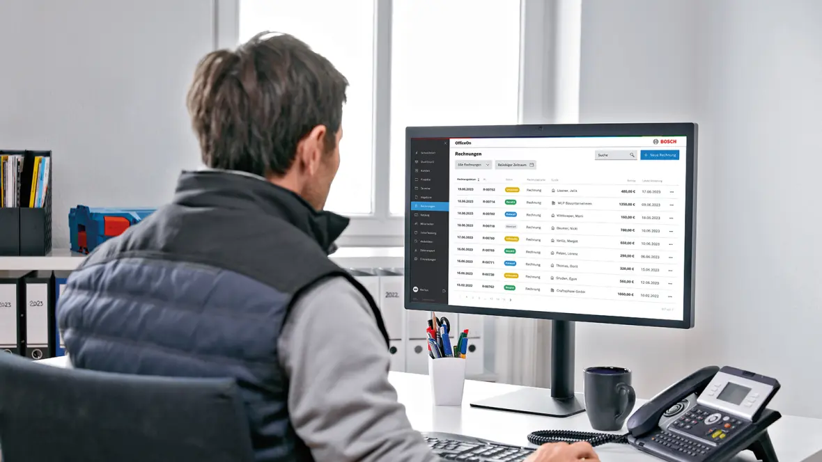 Ein Mann sitzt an einem Computer und arbeitet daran,