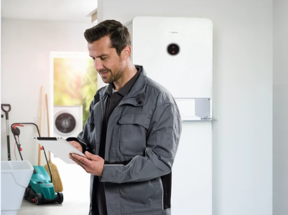 Bosch Installateur hat ein Tablet in der Hand und steht in einer Garage.