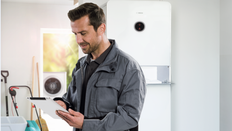 Bosch Installateur hat ein Tablet in der Hand und steht in einer Garage. Bosch Installateur hat ein Tablet in der Hand und steht in einer Garage.