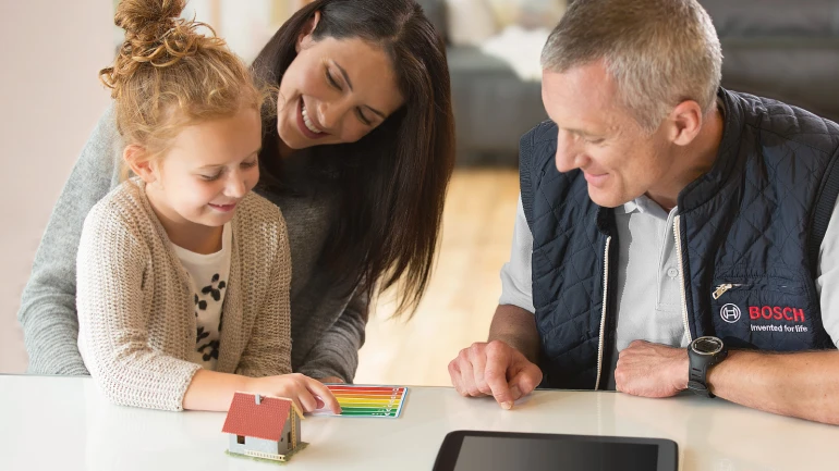 Bosch Installateur erklärt Frau mit Kind die Anforderungen der Energieeinsparverordnung.