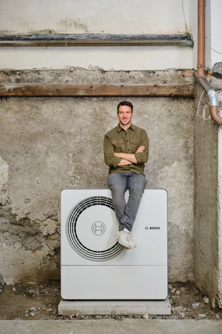 .Felix Neureuther (Skirennläufer) sitzt auf der 6800i AW Wärmepumpen Außeneinheit.