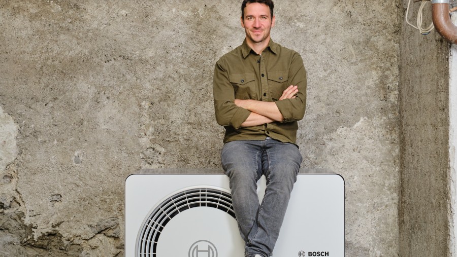 .Felix Neureuther (Skirennläufer) sitzt auf der 6800i AW Wärmepumpen Außeneinheit.