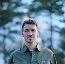 Felix Neureuther steht auf einer Waldlichtung und schaut in die Kamera..