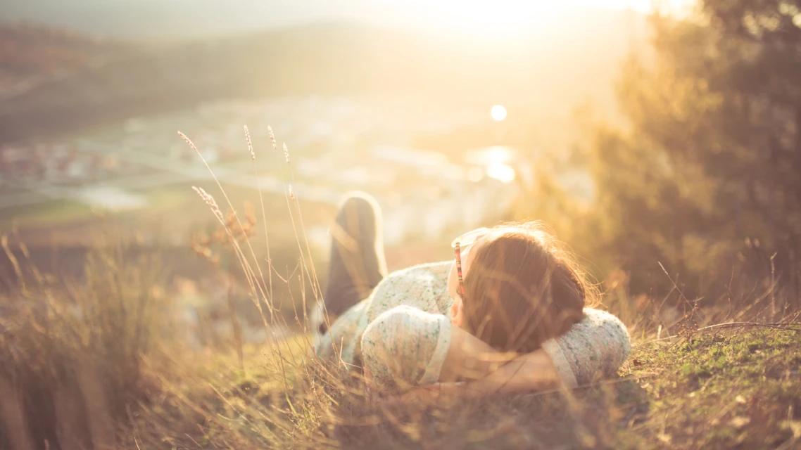 Förderung für Solarthermie, Kind liegt im Sonnenschein im Gras