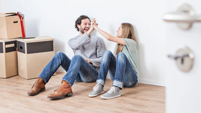 Mann und Frau klatschen ein, während sie auf dem Boden nebeneinander sitzen.