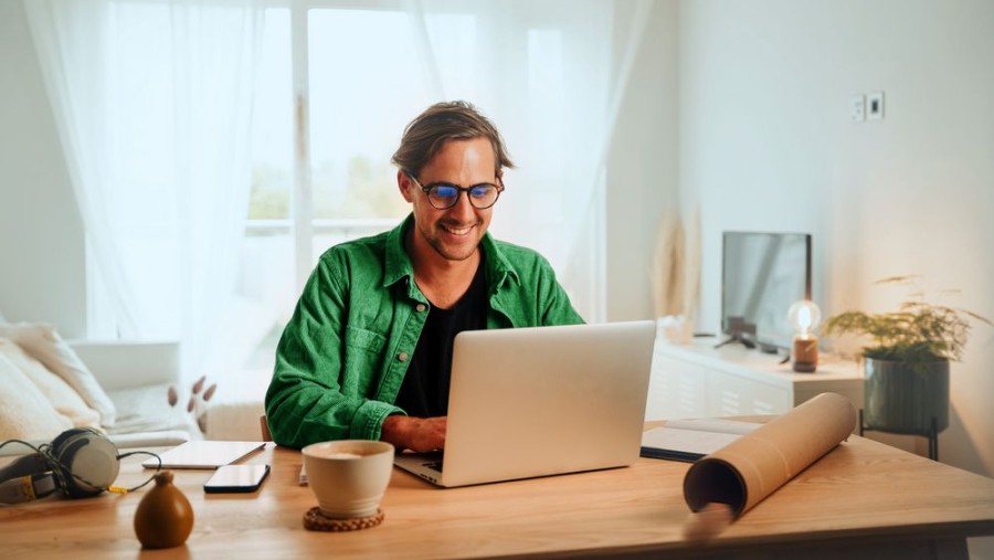 Mann sitzt am Laptop und vergleicht Thermostate für die Bosch Infrarotheizung Mann sitzt am Laptop und vergleicht Thermostate für die Bosch Infrarotheizung