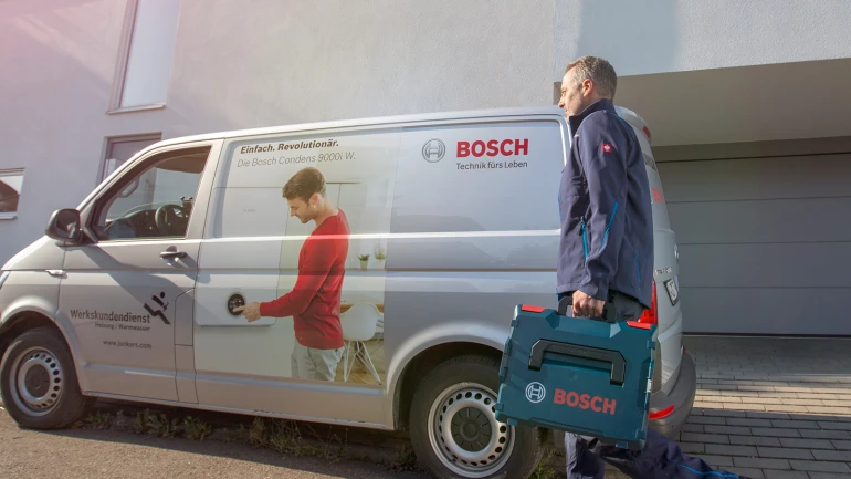 Installateur läuft vor seinem Auto zu einem Haus hin
