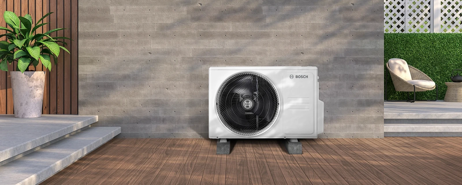 Eine Klimaanlagen Außeneinheit mit eingebautem Ventilator steht vor der Wand eines Gebäudes auf einem Fundament.