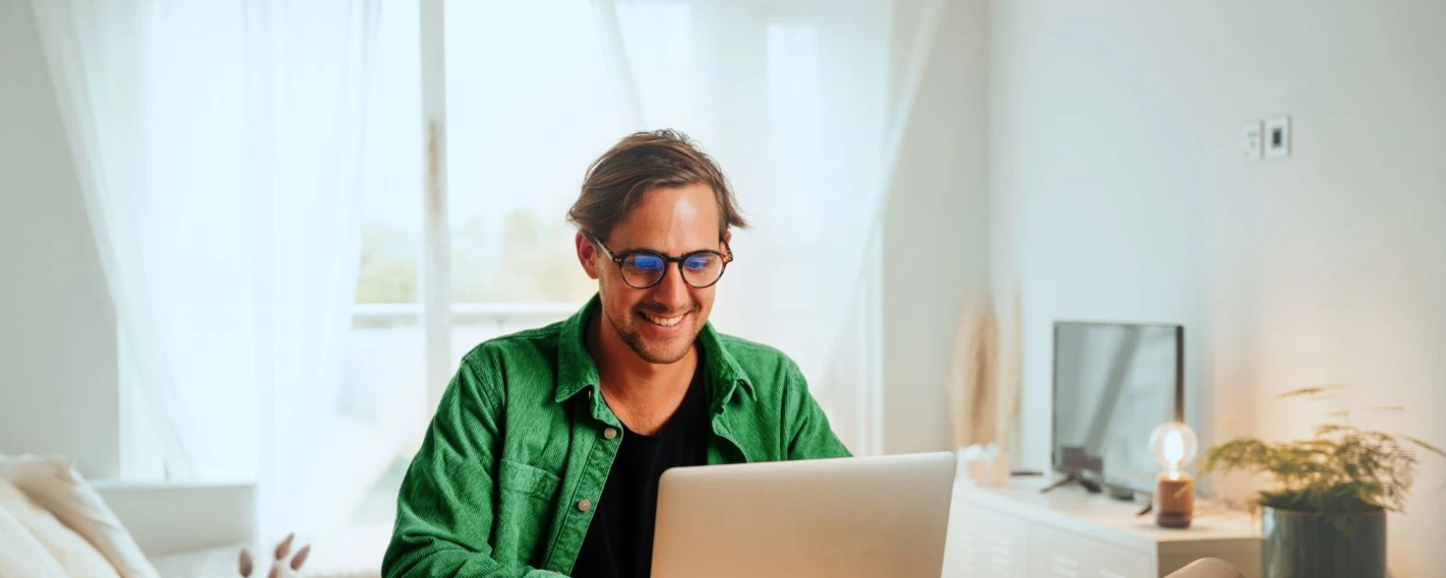 Mann sitzt am Laptop und steuert seine Bosch Infrarotheizung aus der Ferne